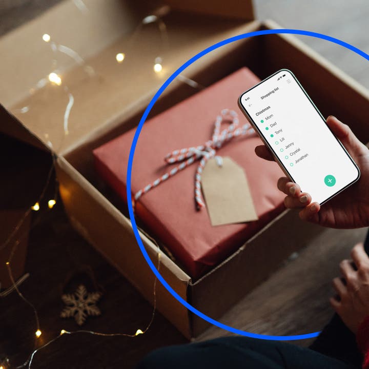 Person holding cellphone with a gift package in the background